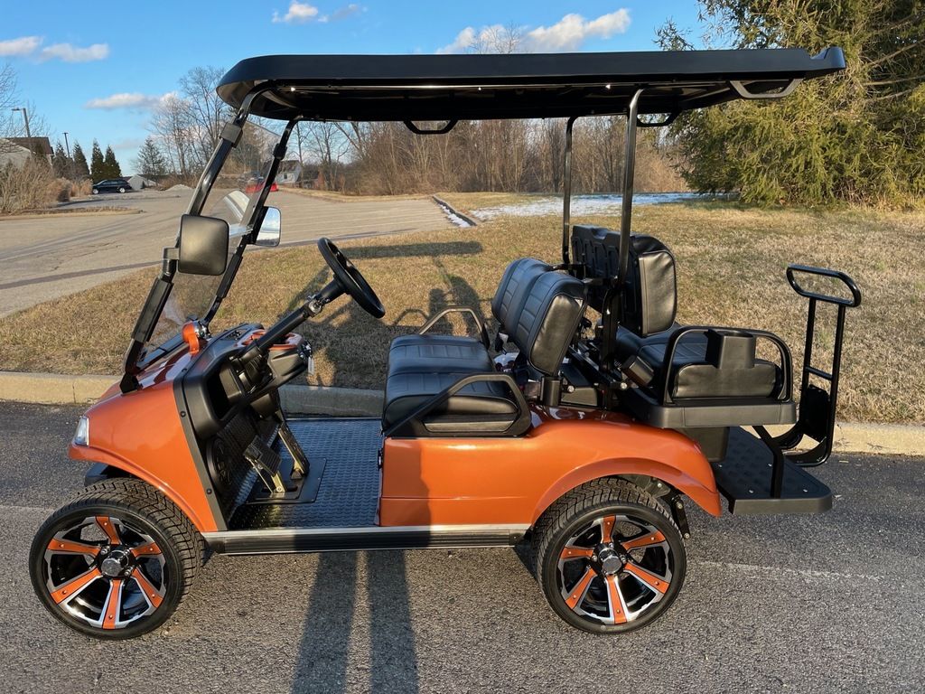 An orange custom 2022 Evolution Electric Vehicles Classic 4 Pro golf cart.